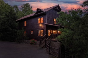 Surrounded by lush greenery, this cabin features a spacious porch and a staircase leading to the entrance.