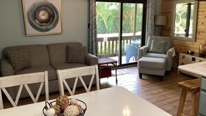 Een gezellige woonkamer met een bank, fauteuils, een eettafel en uitzicht door een schuifdeur op een terras.