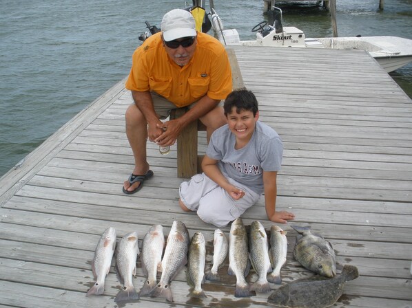 A wooden dock with a row of fish laid out on the deck.