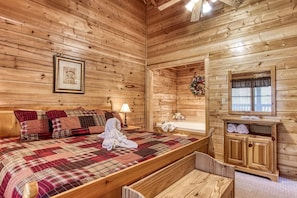 Relax in this inviting bedroom with a large bed, wooden bench, and a table with a lamp.