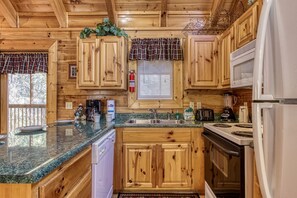 Kitchen features wooden cabinets, granite countertop, stainless steel sink, refrigerator, stove, coffee maker, and blender.