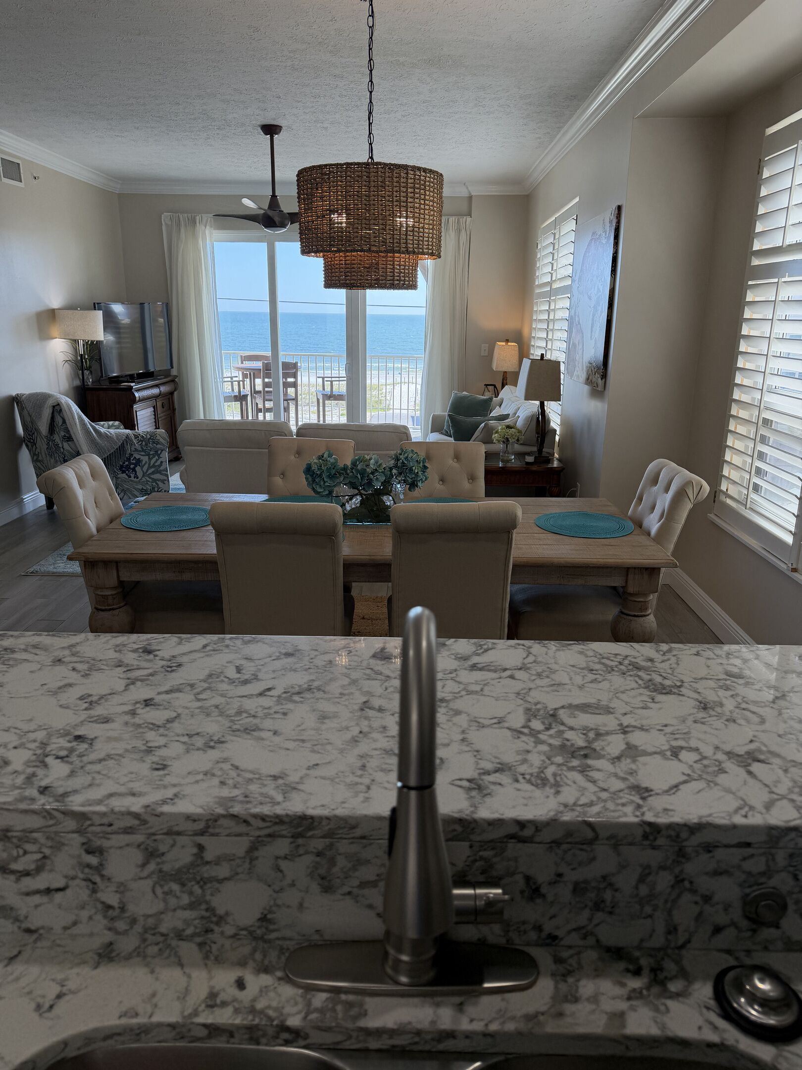 A dining area with a large table, chairs, and a view of the ocean.