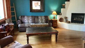 A living room with a wooden coffee table, patterned sofa, and a fireplace. - Easy Walk to the Plaza, Gated Retreat, nearby Ski Santa Fe! (Santa Fe)