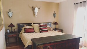 A bedroom with a wooden bed, a headboard with a skull decoration, two bedside tables with lamps, and a wooden floor. - Easy Walk to the Plaza, Gated Retreat, nearby Ski Santa Fe! (Santa Fe)