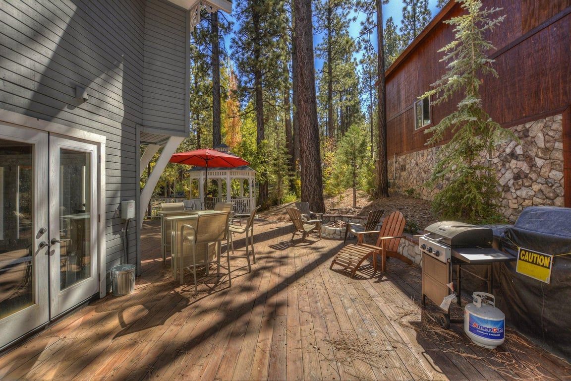 A wooden deck with outdoor furniture, a barbecue grill, and a covered grill area.