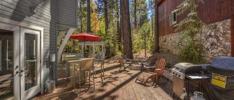 Una terraza de madera con mobiliario exterior, una parrilla y una zona cubierta para asar.