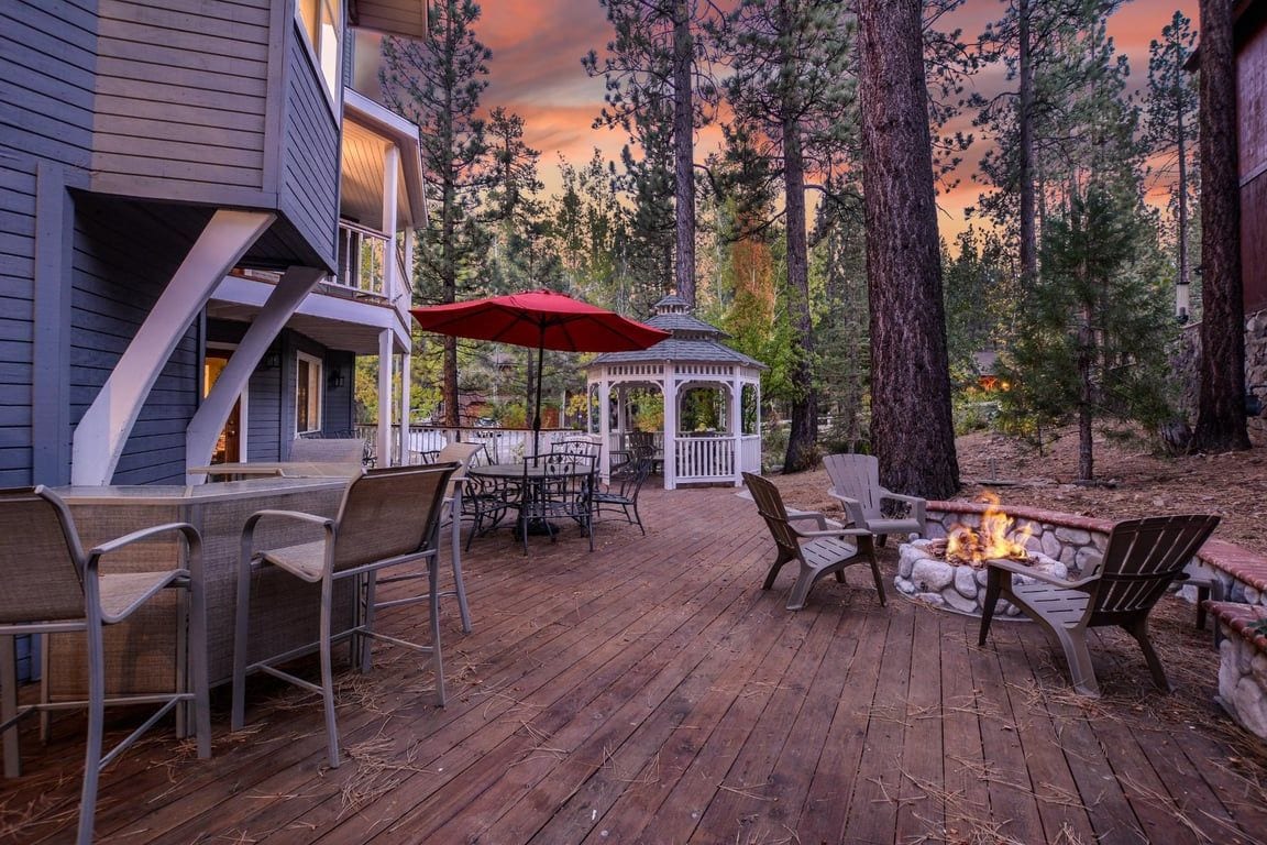 A wooden deck with outdoor seating, a gazebo, and a fire pit.