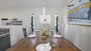 Comedor con una mesa de madera dispuesta para seis personas, rodeado de sillas tapizadas en gris.