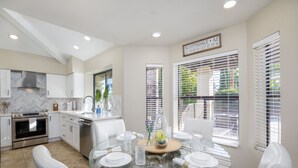 Una cocina moderna con armarios blancos, una mesa de comedor de vidrio y vistas a Scottsdale, AZ.