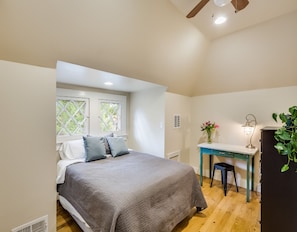 Une chambre à coucher comprenant un lit, un bureau, une chaise, une fenêtre et un ventilateur de plafond.