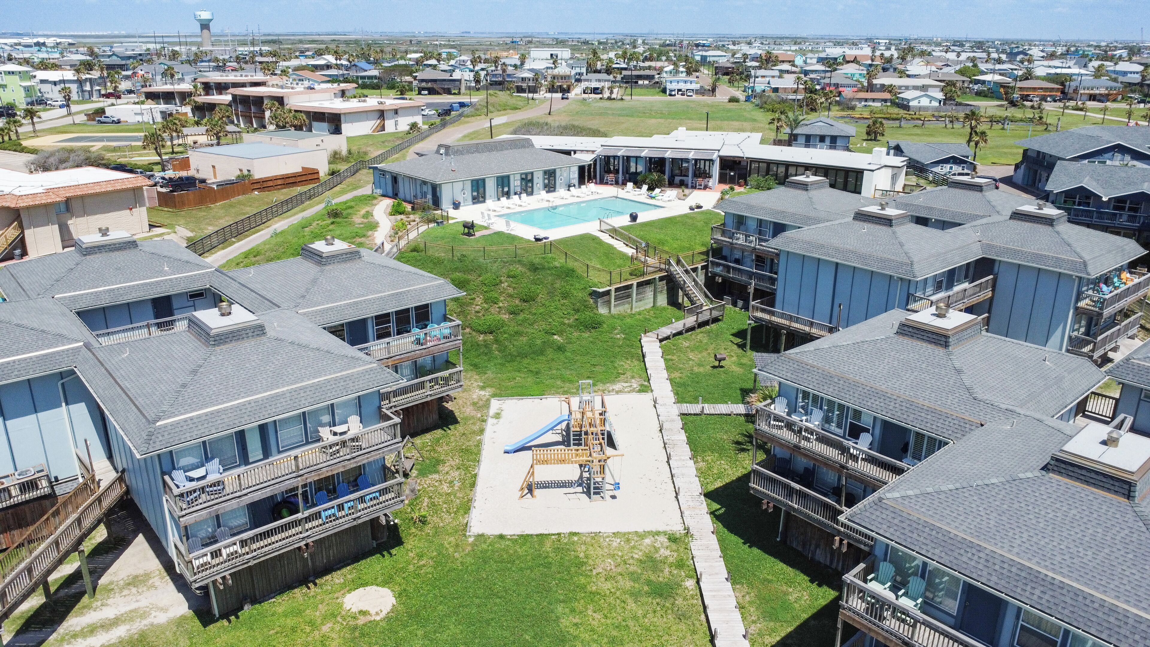 Et boligområde med moderne huse, en swimmingpool og en legeplads.