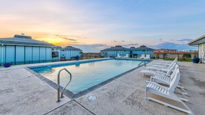 A swimming pool with lounge chairs and a sunset in the background. - Views, swimming pool, boardwalk to the beach, picnic tables, play area, communit (Port Aransas)
