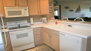 A kitchen with white appliances, wooden cabinets, a sink, and a coffee maker.