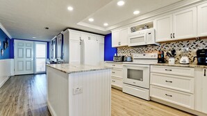 A modern kitchen with white cabinetry, a central island, and a microwave above the stove.