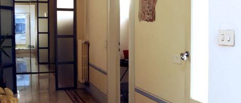 A hallway with a tiled floor, a door with a decorative panel, and a radiator.
