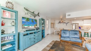A living room with a blue sofa, a coffee table, and a bookshelf with a 'BEACH' sign. - This fabulous upscale condo, complete with elevator access, sits right on the sh (Port Aransas)