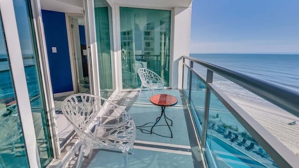 A balcony with glass doors, a white chair, and a small table.