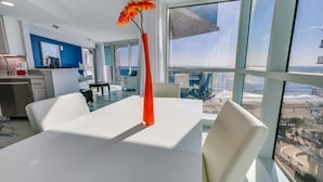 A modern hotel room with a large window offering a view of the beach and ocean.
