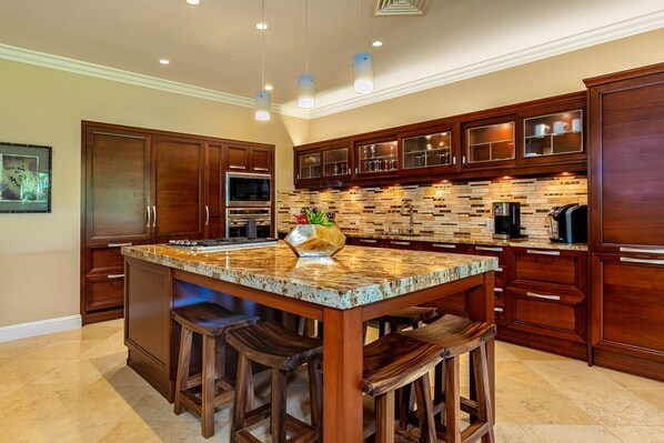 A spacious kitchen with a large island, wooden cabinets, and a brick backsplash.