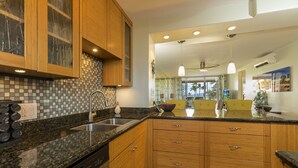 A modern kitchen with granite countertops, wooden cabinets, and a stainless steel sink.
