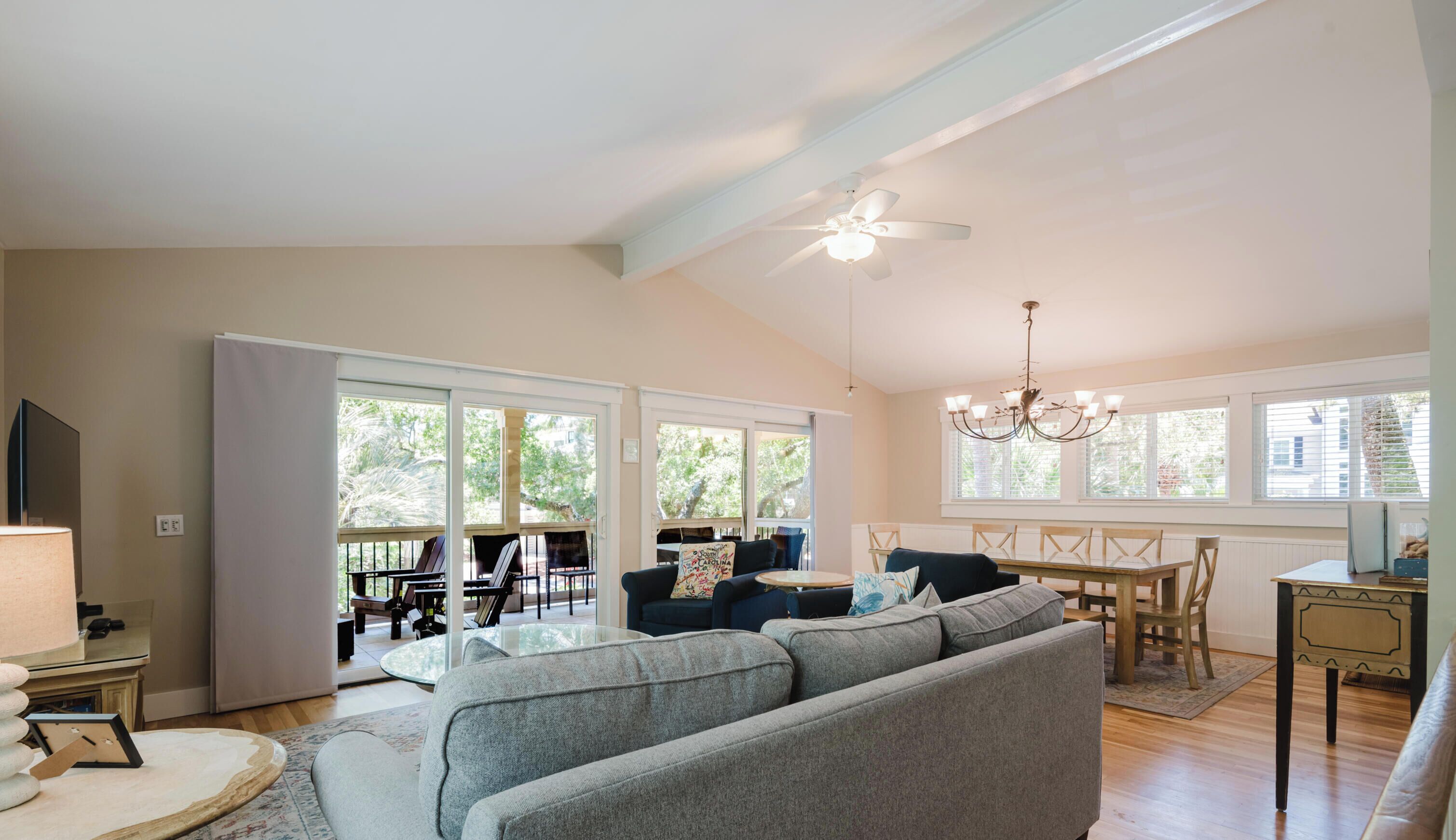A spacious living area with a large sofa, a dining table, and a ceiling fan.