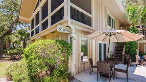 A two-story building with a 'NO DIVING' sign, outdoor seating with chairs and a table, and a staircase leading to the upper level.