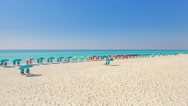 Une plage bordée de rangées de parasols colorés et de chaises de plage.