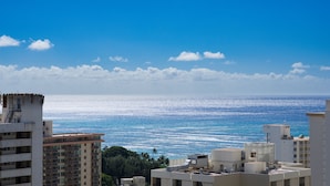 A coastal cityscape with high-rise buildings, a clear blue sky, and a view of the ocean.