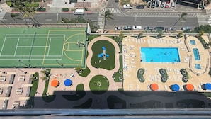 An aerial view of a sports facility with a basketball court, a swimming pool, and outdoor seating areas.