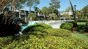 Un hotel con piscina, rodeado de vegetación cuidada y palmeras.