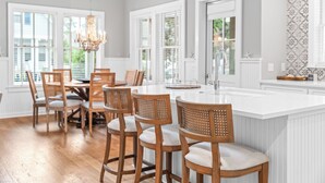 Una cucina con sedie di legno, un'isola bianca e un lampadario.