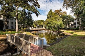 Ein friedlicher Innenhof mit Teich, einer Holzbrücke und üppigem Grün.
