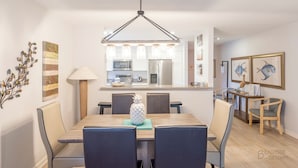 Een moderne eethoek met een houten tafel, blauwe stoelen en een hanglamp.