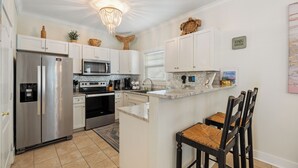 Cocina moderna con armarios blancos, electrodomésticos de acero inoxidable y una isla central con taburetes de bar.