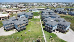 Complejo residencial con varias construcciones de dos pisos, cada una con balcones y un patio central que tiene una piscina.