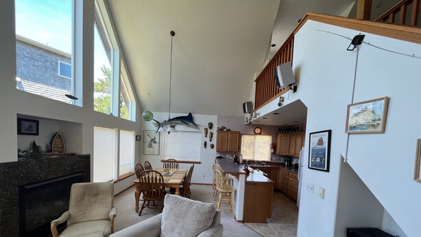 A spacious living area with a fireplace, a dining table, and a kitchen in the background. - Surfrider - Cozy Beach Cabin, Close to Beach, Pool Table (Pacific City)