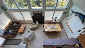 A spacious living area with a sofa, armchairs, a dining table, and a fireplace. - Surfrider - Cozy Beach Cabin, Close to Beach, Pool Table (Pacific City)