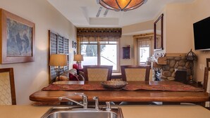 A dining area with a wooden table, chairs, a chandelier, and a stone fireplace. - Steps to American Flyer lift & Stellar Mtn Views! Hot Tub, Free Wifi, Heated Pkg (Copper Mountain)