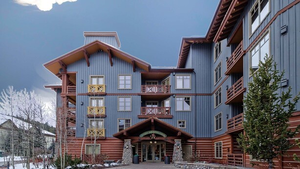 A multi-story lodge with a central entrance, balconies, and a mountain backdrop. - Steps to American Flyer lift & Stellar Mtn Views! Hot Tub, Free Wifi, Heated Pkg (Copper Mountain)