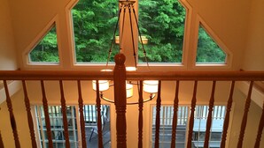 Un escalier en bois offrant une vue sur une terrasse et sur du mobilier d’extérieur.