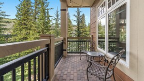 Ein Balkon mit Backsteinboden, Metallgeländer und zwei Metallstühlen.