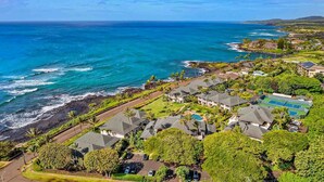 A coastal residential area with houses, a tennis court, and a view of the ocean.