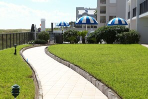 Stroll through the beautifully manicured lawn, lined with a brick wall and shaded by striped umbrellas.
