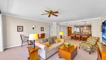 A living room with a sofa, coffee table, and a dining area with chairs and a lamp.