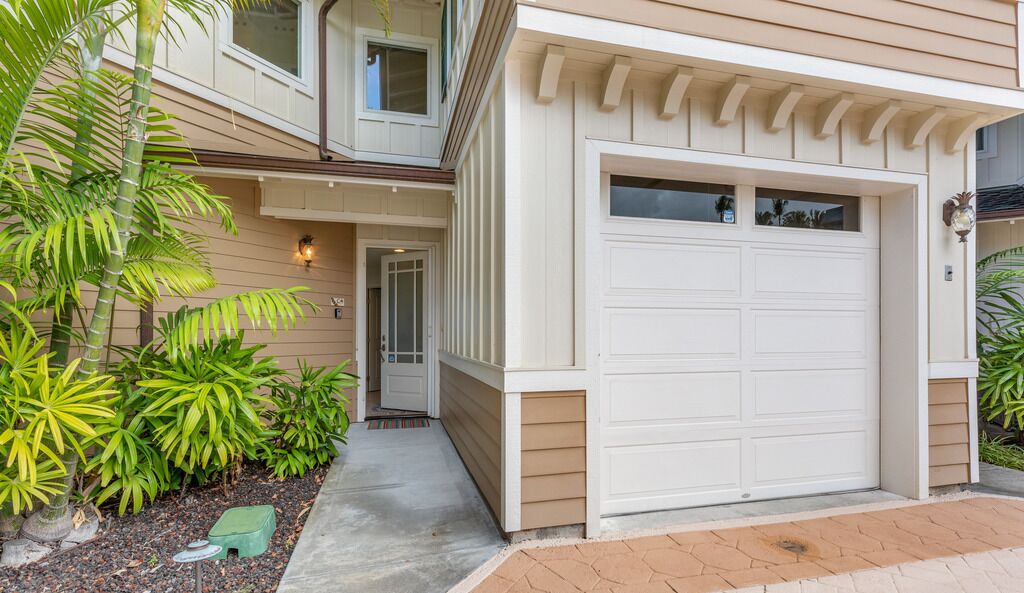 A two-story house with a white garage door, a front entrance with a door, and a small porch area.