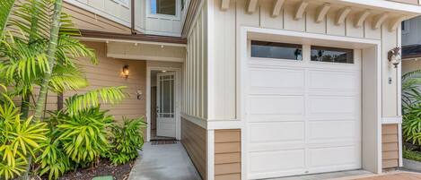 A two-story house with a white garage door, a front entrance with a door, and a small porch area.