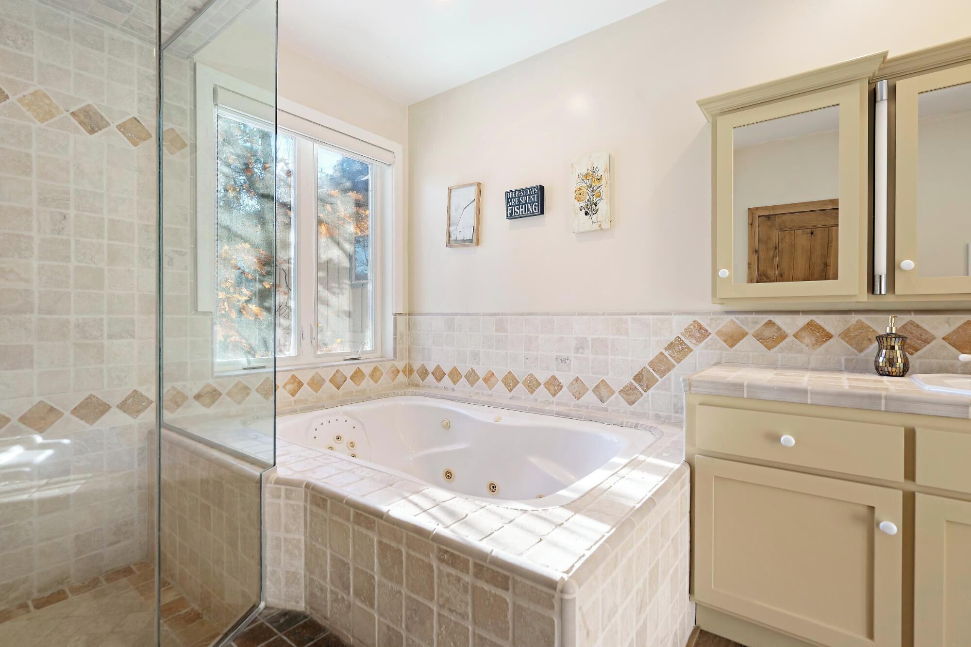Une salle de bain dotée d’une grande baignoire, d’une douche à parois de verre et d’un meuble-lavabo avec un miroir.