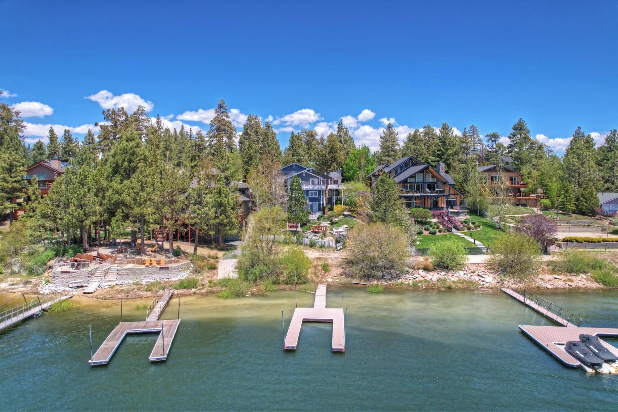 A lakeside property with multiple houses, a dock, and a well-maintained garden.