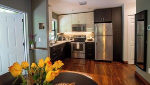 A modern kitchen with stainless steel appliances, dark cabinets, and a wooden floor. - Coconut Grove Garden Cottage • Private Retreat with Free Parking & Full Kitchen (Miami)