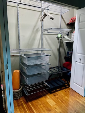 A storage area with metal shelves, baskets, and a rolled-up mat.
